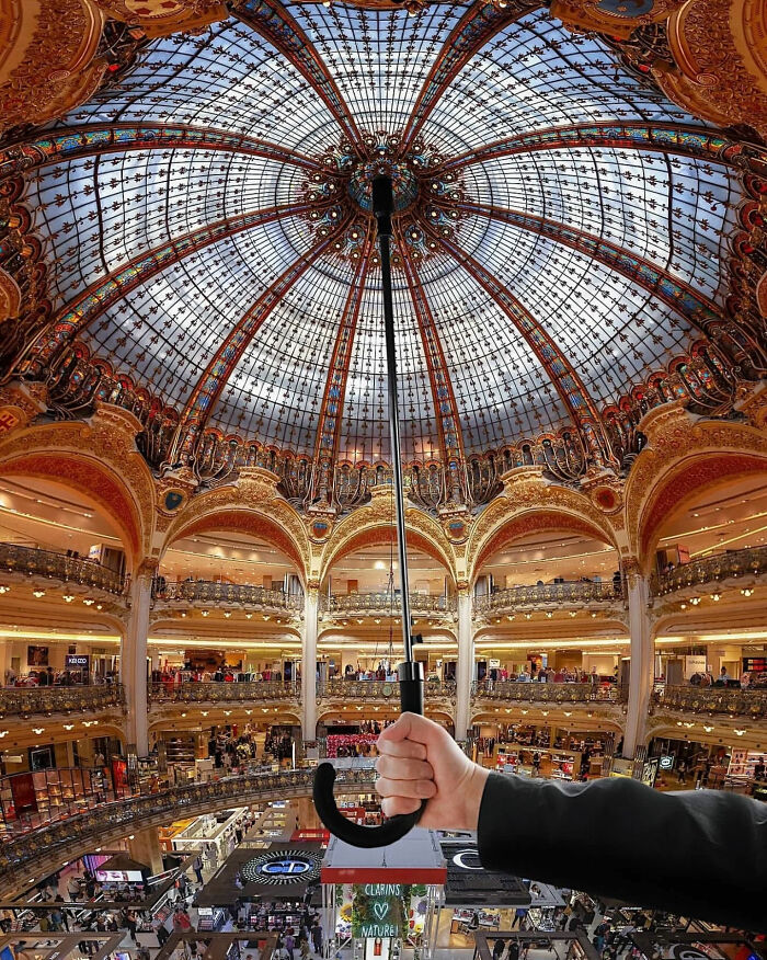 Hand holding an umbrella inside a grand hall with a stunning glass dome, a great photo.