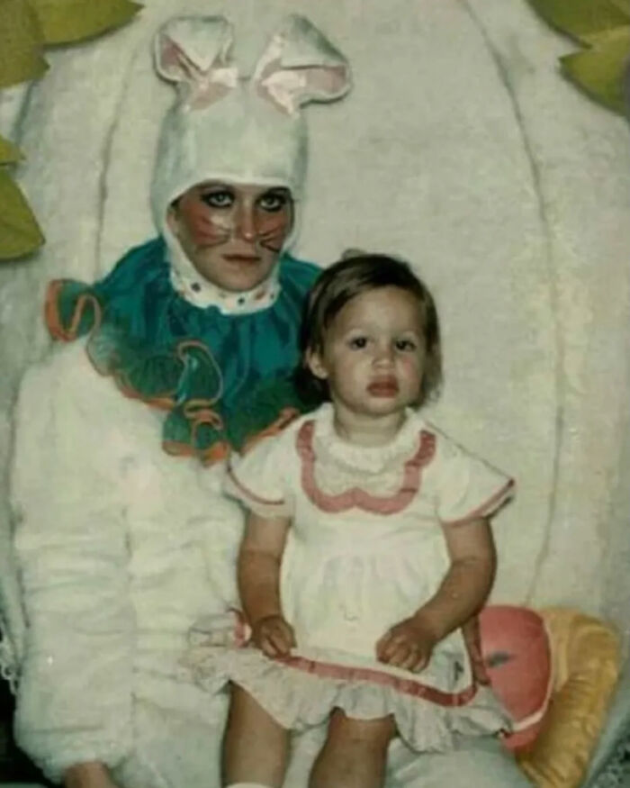 A young child sitting on the lap of an adult in a somewhat eerie bunny costume, a truly great photo, legends of the internet.