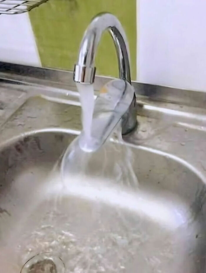 Water flowing from a kitchen faucet into a clear plastic cup, then overflowing into the sink, a legend of the internet.