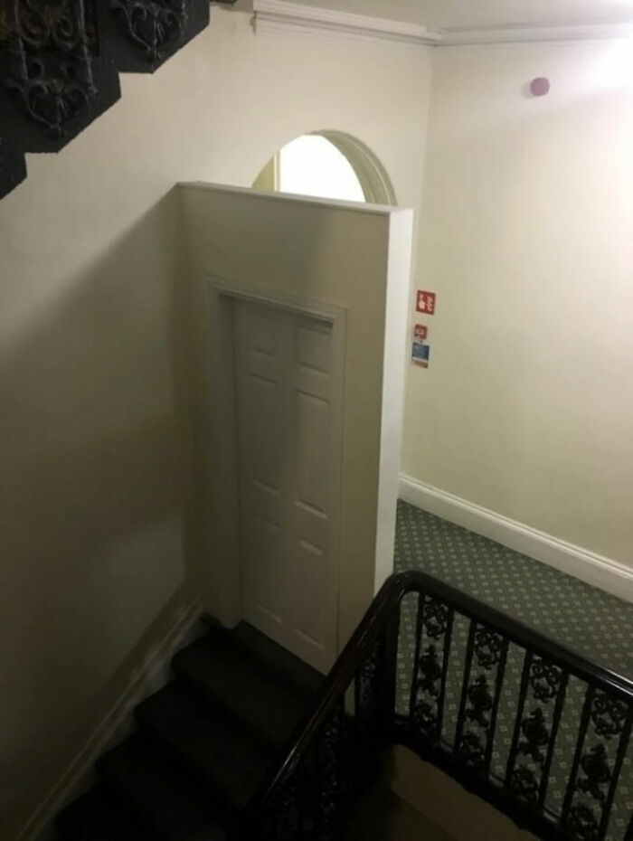 A white door built into a wall under an archway, at the top of a dark staircase, one of the great photos.