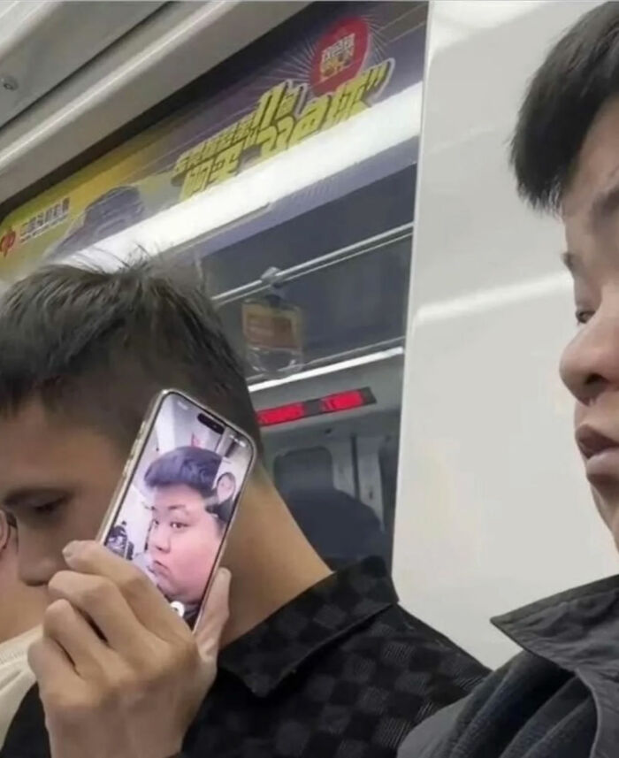 A person on a subway holds a phone displaying a selfie of another person, a great photo that became a legend.