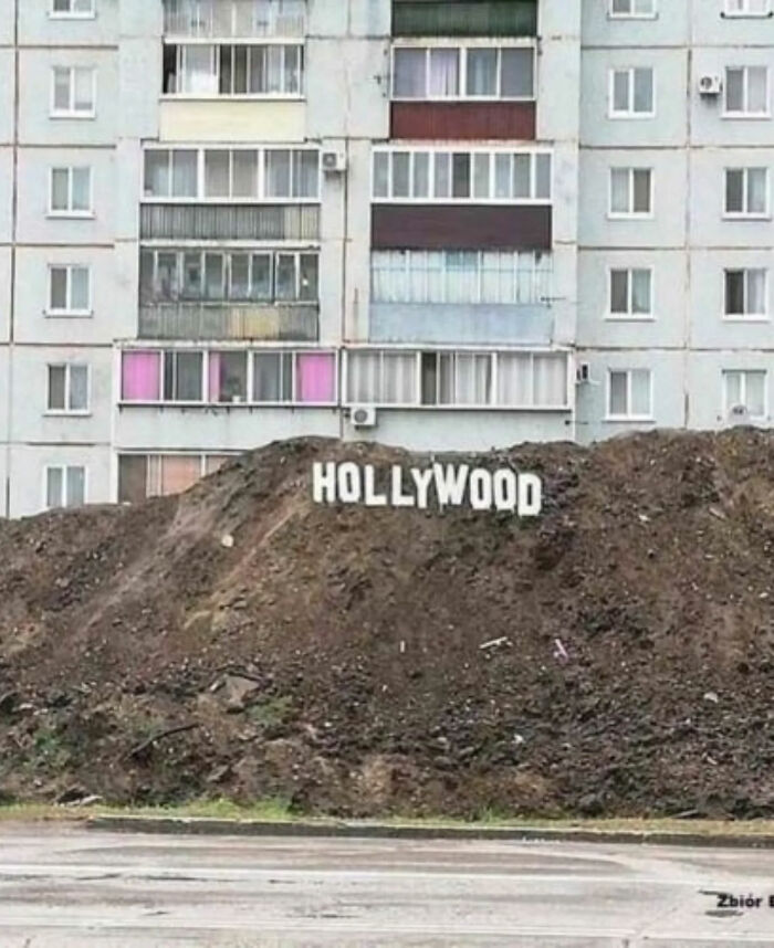 A small Hollywood sign is placed on a dirt mound in front of an apartment building, a funny image that became an Internet legend.