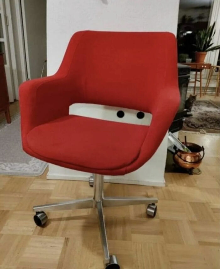 A red office chair with a white stripe and two black circles that resemble Lightning McQueen's face, a great photo.