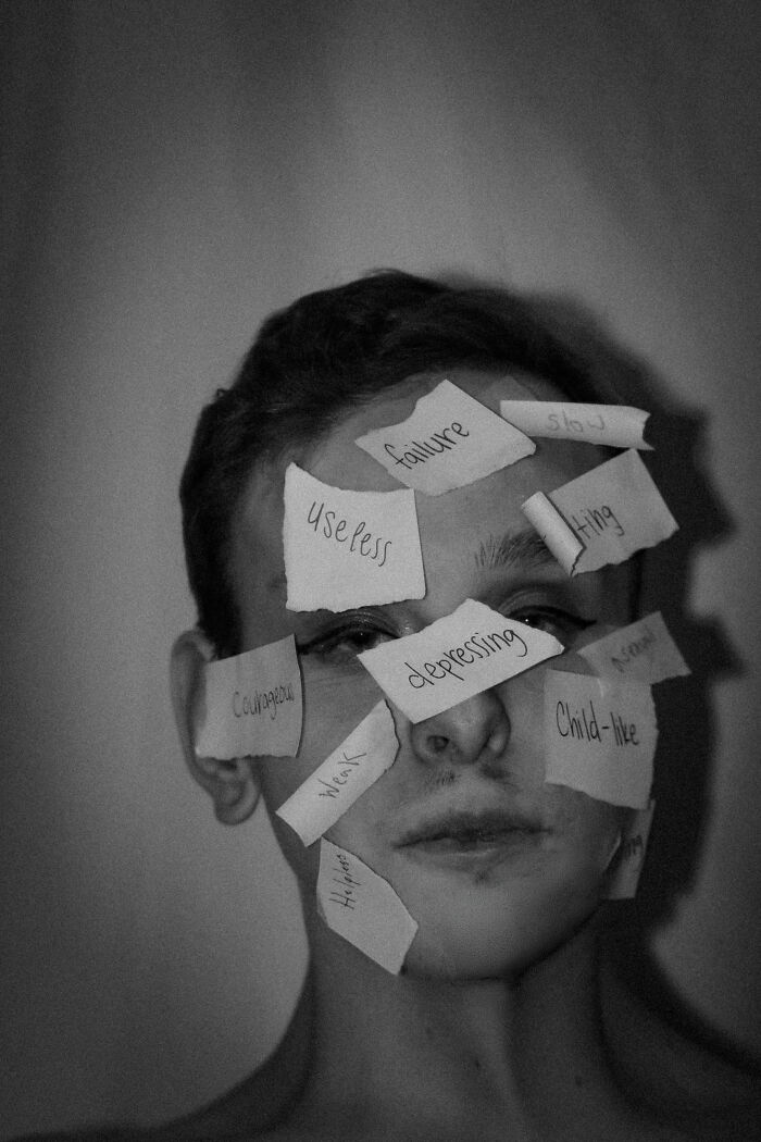 Person's face covered with negative thought pattern words on paper
