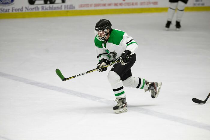 Youth hockey player skating fast on ice rink during game