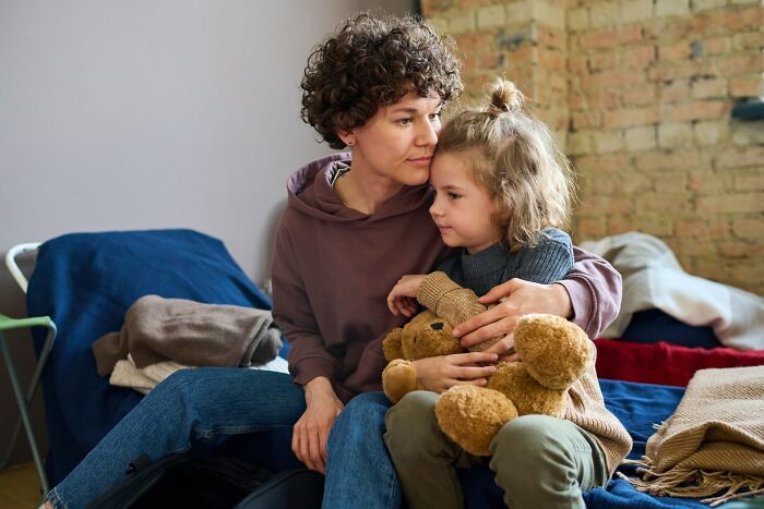 Mother comforting child holding teddy bear at home