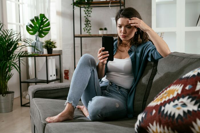 A woman looking stressed while checking her phone, reflecting a teacher's reaction to messages from entitled parents.