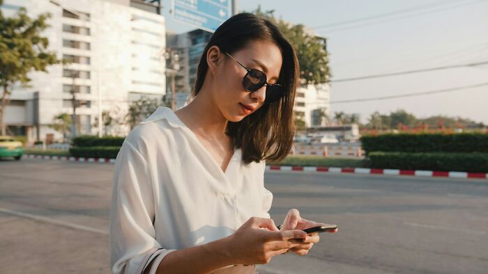 Woman using smartphone outdoors representing shocking things found on partner's phone