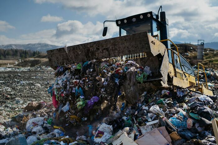 A bulldozer pushing a large pile of garbage at a landfill, illustrating one of many unsolved mysteries.