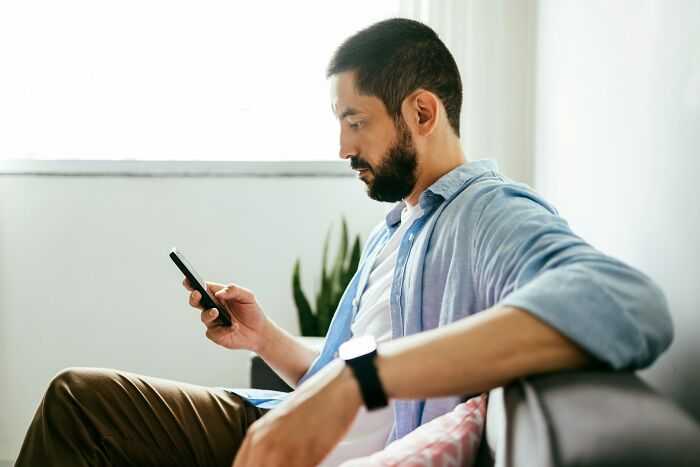 Man sitting on couch focused on checking phone screen