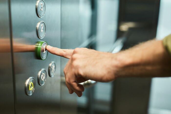A hand pressing an elevator button, an experience that could be creepy.