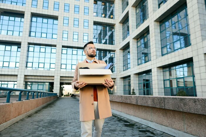 Man carrying box outside office building showing employee walkouts