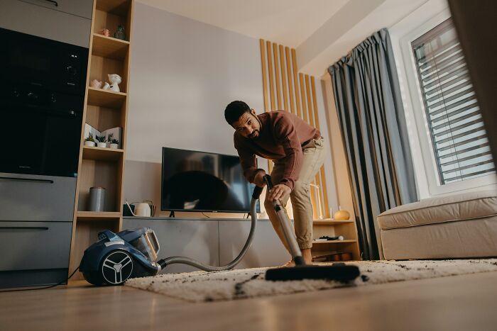 Man vacuuming living room, showing a moment women decide to marry their partner.