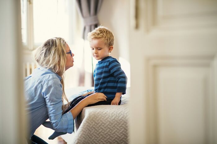 Woman talking to a young child on a bed, suggesting healthy communication to avoid intense stress and burnout.