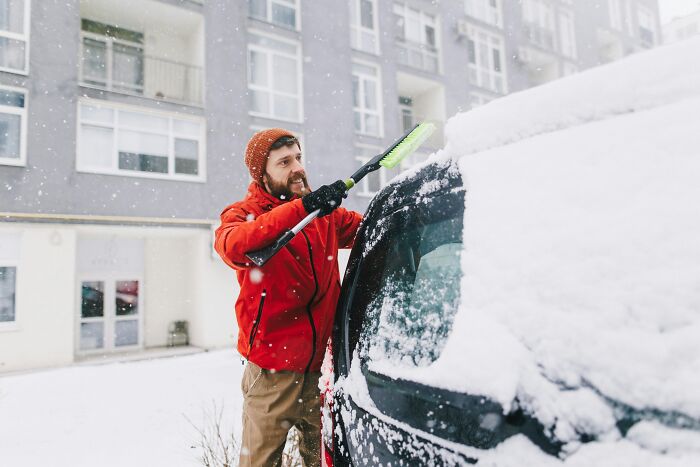 A man clearing snow from his car in winter, not directly related to women who marry their partner.