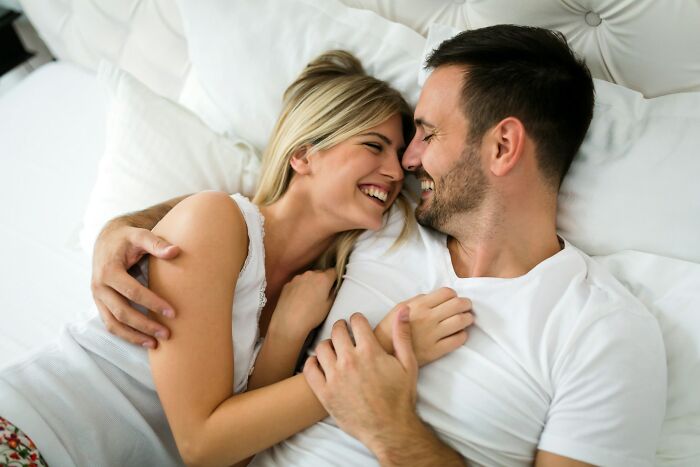 Happy couple embracing and smiling in bed enjoying intimate moment