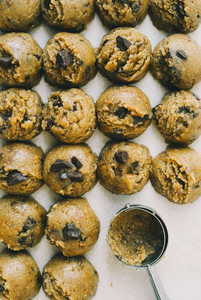 Scoops of raw chocolate chip cookie dough on parchment, fresh food facts on treats
