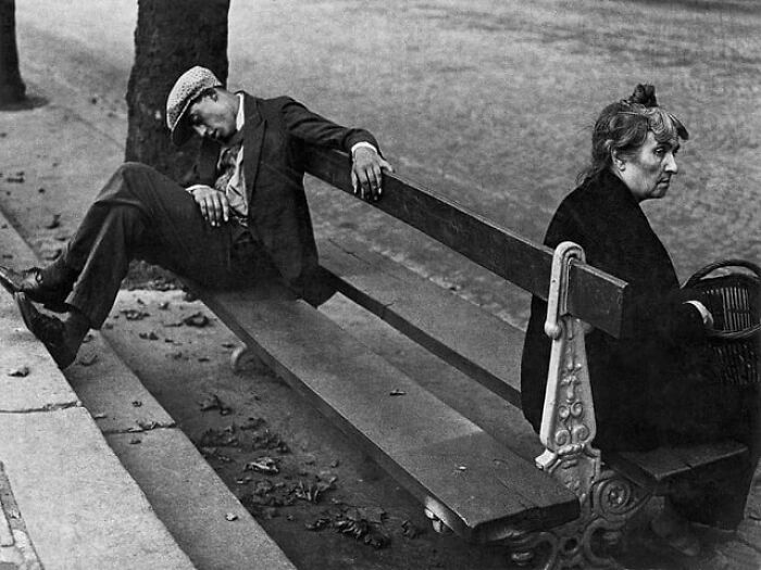 Vintage black and white photo of two people sitting on a park bench looking away