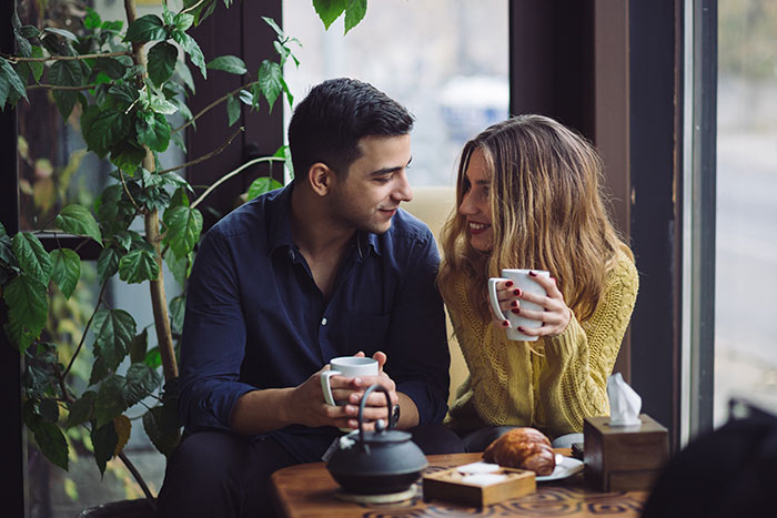 Couple smiling and drinking coffee together discussing wife's affair partner Couple smiling and drinking coffee together discussing wife's affair partner