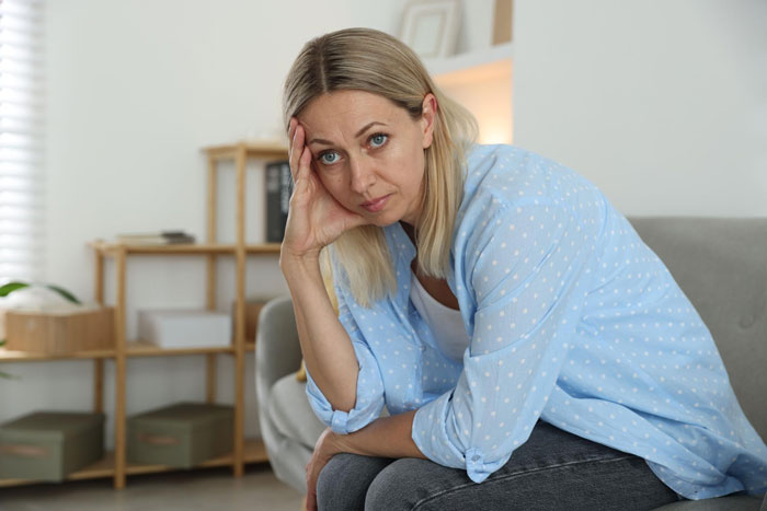 Worried woman sitting on couch reflecting on family issues Worried woman sitting on couch reflecting on family issues
