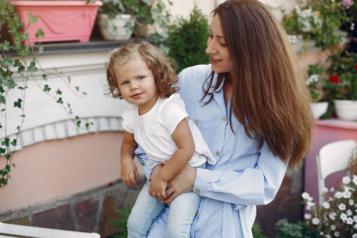 Woman holding toddler daughter outside in garden Woman holding toddler daughter outside in garden