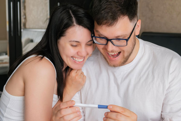 Couple happily looking at positive pregnancy test Couple happily looking at positive pregnancy test