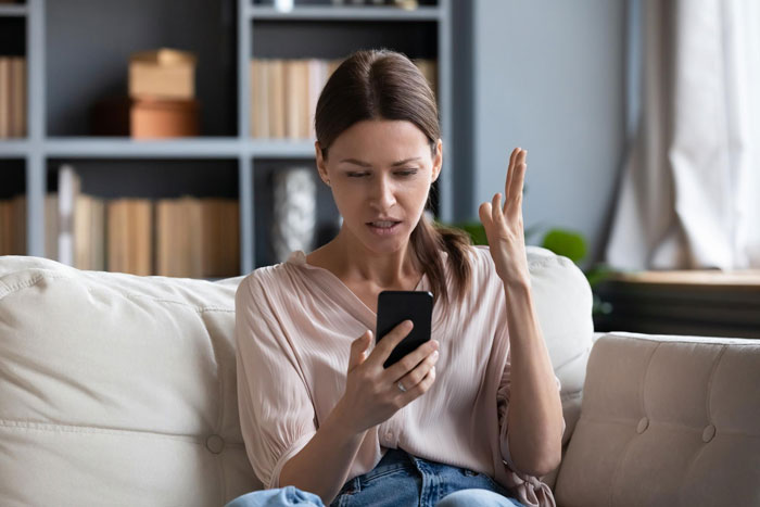 Woman upset while looking at smartphone, reflecting family conflict Woman upset while looking at smartphone, reflecting family conflict
