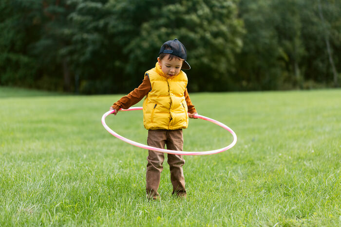 Young child playing with hula hoop outdoors in generous joyful moment
