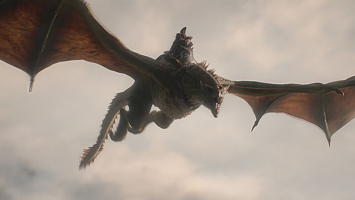 A dragon with a rider soars through the sky, a powerful presence in the House of the Dragon series. A dragon with a rider soars through the sky, a powerful presence in the House of the Dragon series.