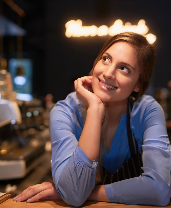A smiling barista leaning on a counter, looking up thoughtfully, depicting things people never tell their partners.