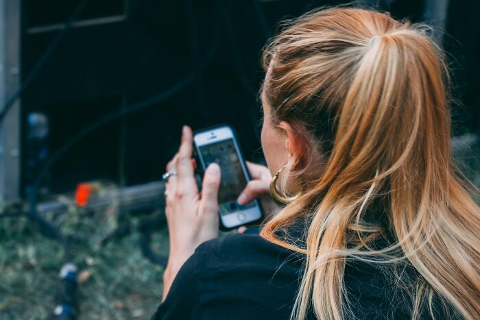 Woman using smartphone capturing photo or text on phone with blond hair