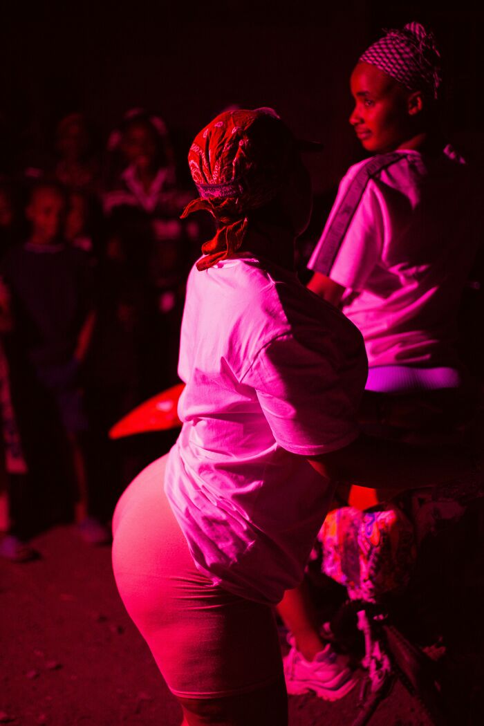 Two women in red-tinted light, one facing away, showing men's turn offs women roll their eyes at.
