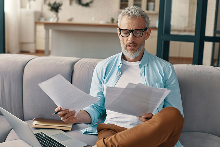 Man reviewing documents confused about HOA water access and membership issues at home Man reviewing documents confused about HOA water access and membership issues at home