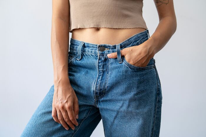 A woman stands in jeans and a crop top, hand in pocket, a confident moment to marry her partner.