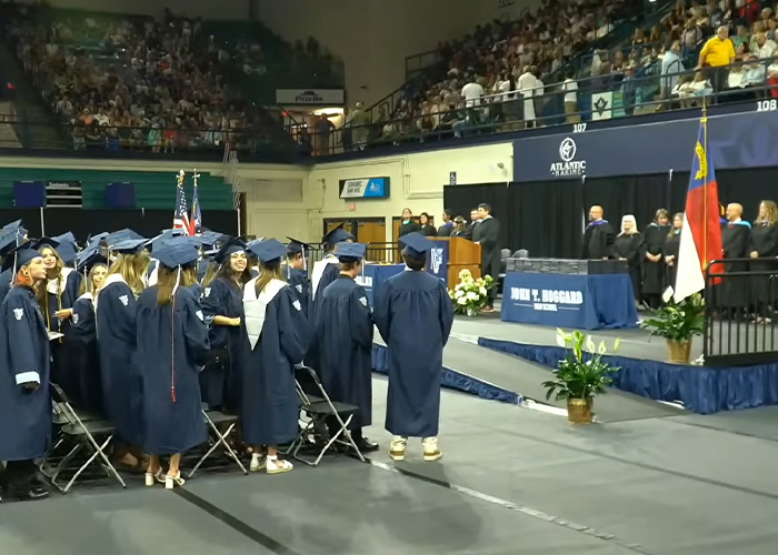 Graduating students standing during HS valedictorian speech at ceremony Graduating students standing during HS valedictorian speech at ceremony