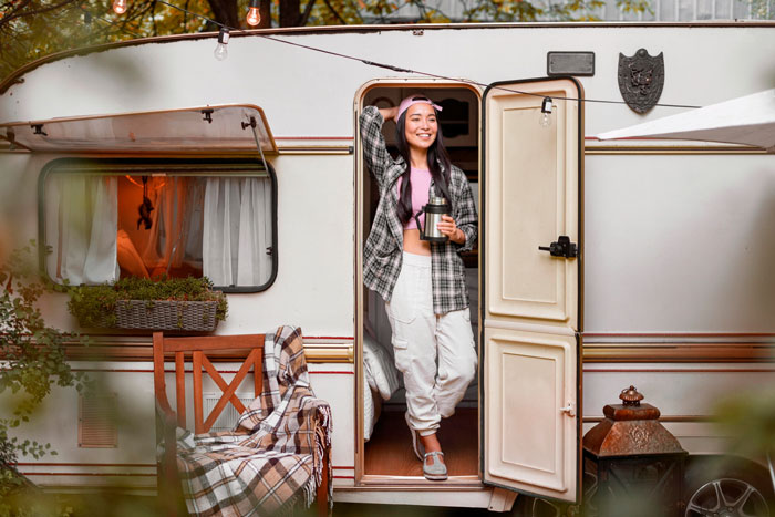 A happy woman standing in the doorway of a caravan, representing a couple starting life together.