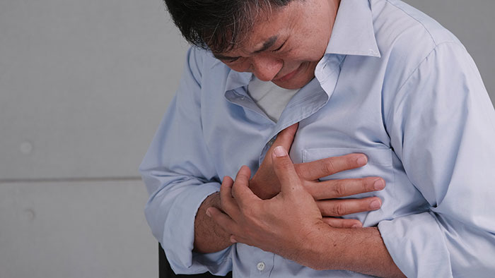 A man clutching his chest in pain, indicating a serious medical symptom that doctors warn against ignoring.