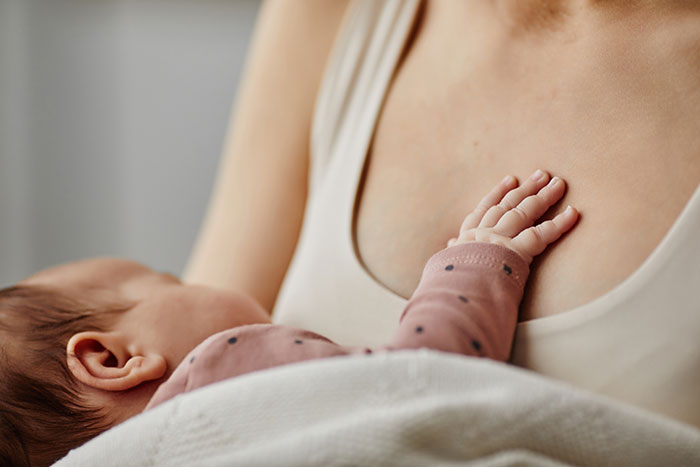 A baby's hand resting on a parent's chest, illustrating medical symptoms not to ignore in new parents.