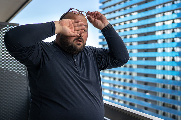 A man rubbing his eyes, looking tired, a medical symptom that could indicate a larger underlying problem.