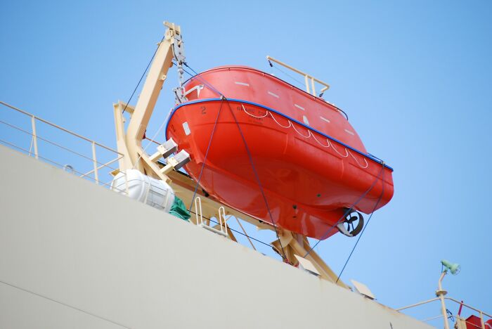 An orange lifeboat hanging from a ship, representing one of many unusual jobs people somehow managed to get hired for.