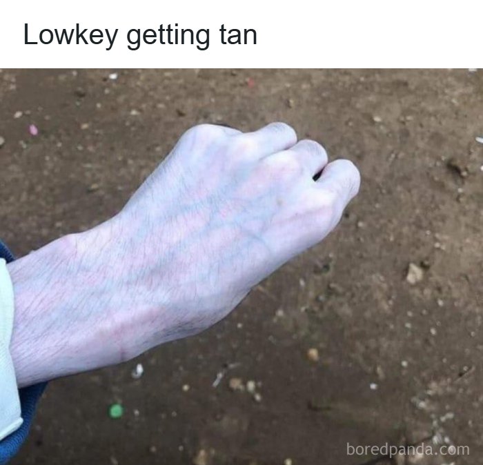 Pale hand outdoors with caption lowkey getting tan