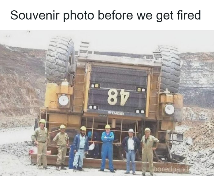 Group of workers posing in front of overturned heavy machinery before getting fired