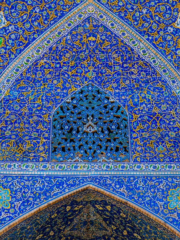Detailed Persian tilework with blue and gold arabesque patterns on mosque wall