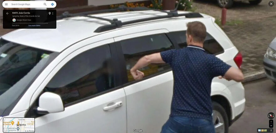 A bizarre Google Street View photo showing a man in a blue shirt and jeans appearing to punch a white car.