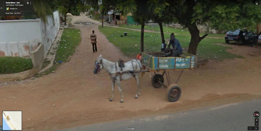 A funny Google Street View photo capturing a horse-drawn cart on a dirt road with people nearby.