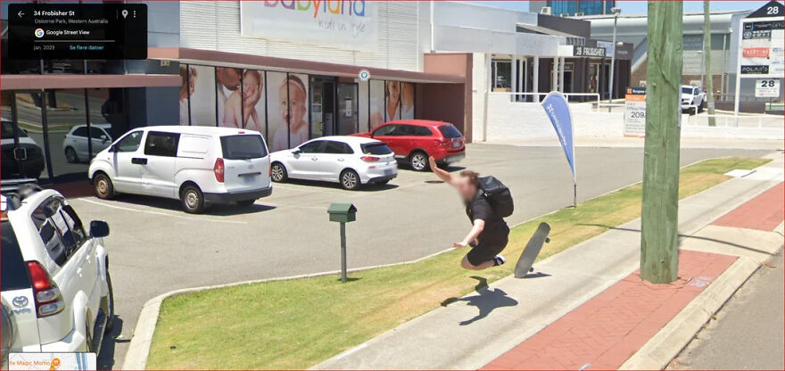 A funny Google Street View photo of a person jumping off a skateboard in a parking lot, blurring their face.
