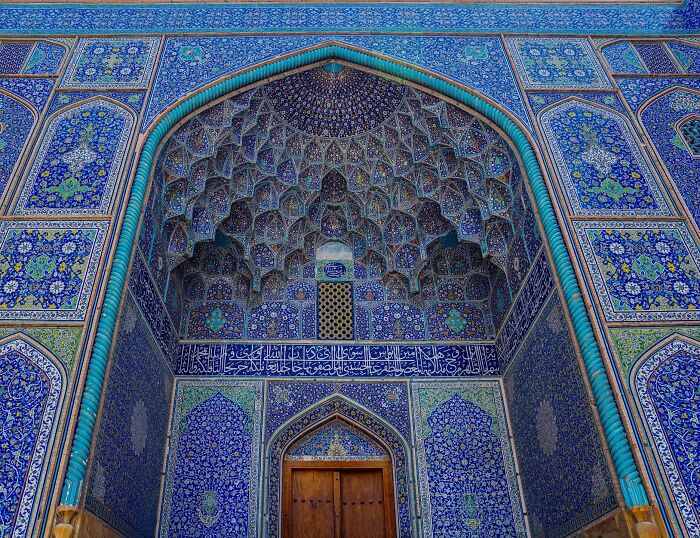 Ornate blue classical Persian tile arch with muqarnas and detailed geometric calligraphy