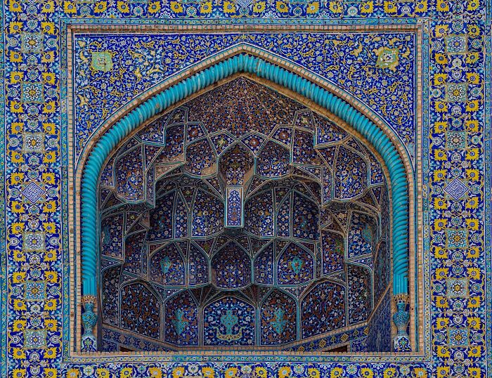 Blue and yellow classical Persian tilework framing a detailed niche with complex geometric patterns
