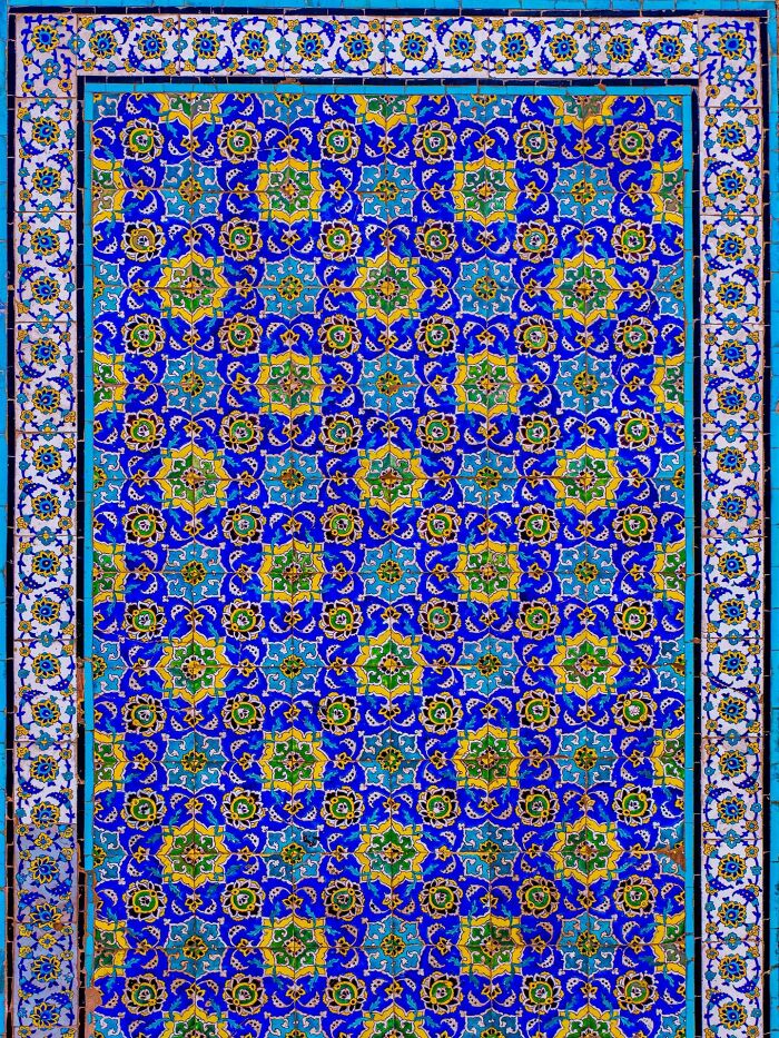 Intricate blue and yellow Persian tile patterns with geometric floral designs