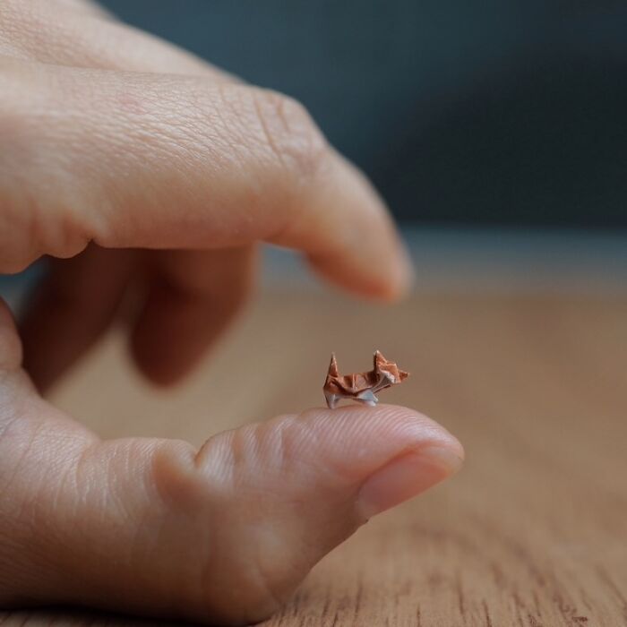 Miniature paper figures: An incredibly small, detailed origami cat perched delicately on a fingertip.